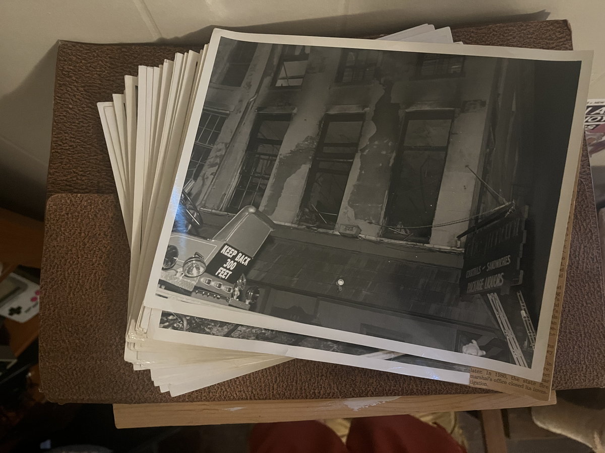 A stack of black-and-white prints; the top one shows a storefront with a balcony.