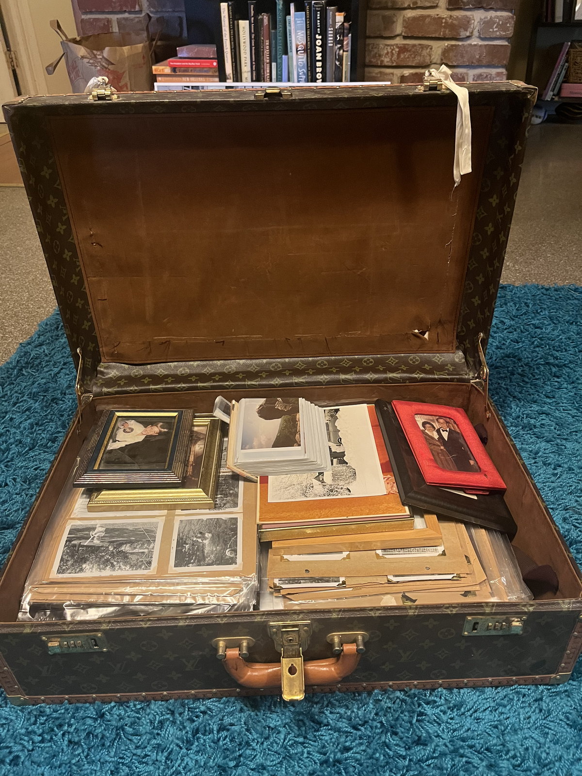 An open steamer trunk packed with boxed slides, loose prints, and a framed photograph.